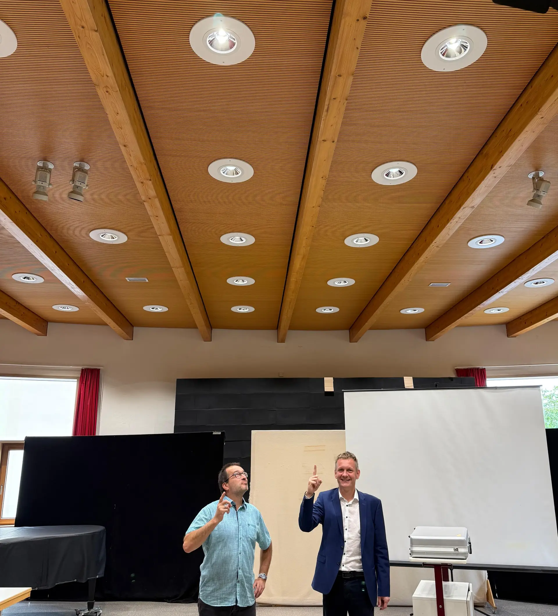 Schulleiter Olaf Küchler und Landrat Dr. Ulli Schäfer begutachten die neue Beleuchtung in der Aula des Osterlandgymnasiums. (